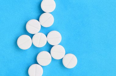 Birkaç beyaz tabletler parlak mavi bir arka plan bir bakteri şeklinde yalan. Tıp ve eczacılık konularda arka plan görüntüsü