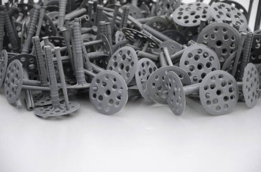 Birçok gri plastik dübel için ısı yalıtımı tespitleme arka plan. Plastik büyük bir yığın yuvarlak delikli şapka yalanlarla Gri köpük polistiren tabakta cıvata.