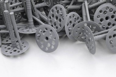 Birçok gri plastik dübel için ısı yalıtımı tespitleme arka plan. Plastik büyük bir yığın yuvarlak delikli şapka yalanlarla Gri köpük polistiren tabakta cıvata.