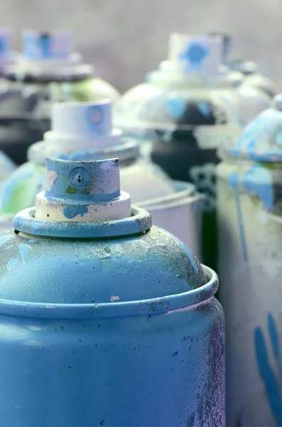 A lot of dirty and used aerosol cans of bright blue paint. Macro photograph with shallow depth of field. Selective focus on the spray nozzle