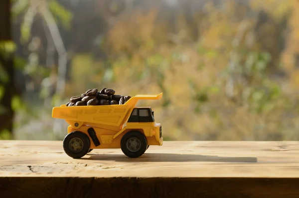 Um pequeno caminhão de brinquedo amarelo é carregado com grãos de café marrom. A ca — Fotografia de Stock