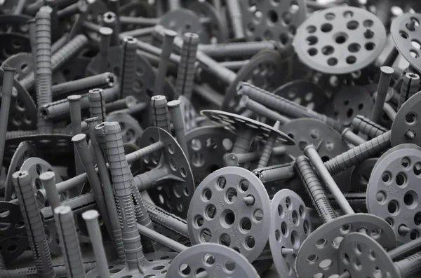Background pattern of many gray plastic dowels fastening for thermal insulation. A huge pile of fixtures for the installation of expanded polystyrene plates for the insulation of the building walls — Stock Image Background Pattern Many Gray Plastic Dowels Fastening Thermal Insulation Huge Royalty Free Stock Images