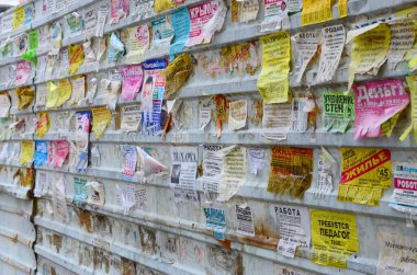 Kharkov, Ukrayna - 24 Haziran 2018: Grunge Mesaj Kurulu birçok reklamla birlikte. İnsanlar beyaz kağıda reklam ve bilgi yayıyorlar, metal çitlere asmaktansa.