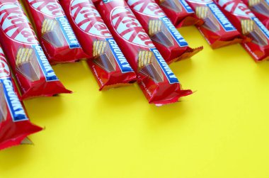 Kırmızı ambalajlı Kit Kat çikolataları sarı arka planda yatıyor. Kit Kat, Birleşik Krallık 'ta Rowntree' s of York tarafından yaratıldı ve şimdi küresel olarak Nestle tarafından üretiliyor.