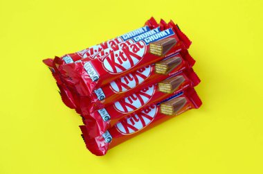 Kırmızı ambalajlı Kit Kat çikolataları sarı arka planda yatıyor. Kit Kat, Birleşik Krallık 'ta Rowntree' s of York tarafından yaratıldı ve şimdi küresel olarak Nestle tarafından üretiliyor.