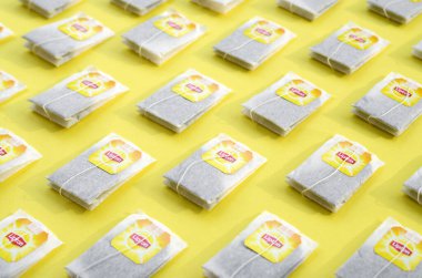 Pastel sarı yüzeyde Lipton Sarı Etiketli siyah çay poşetleri vardı. Lipton dünyaca ünlü bir çay türüdür.