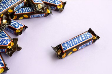 Birçok Snickers çikolatası pastel leylak kağıdının üzerinde yatar. Snickers çikolataları Mars Anonim Şirketi tarafından üretilir. Snickers 1930 yılında Franklin Clarence Mars tarafından yaratıldı.