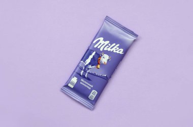 Milka chocolate tablet in classic violet wrapping on lilac background. Milka is brand of chocolate confection originated in Switzerland in 1901 clipart