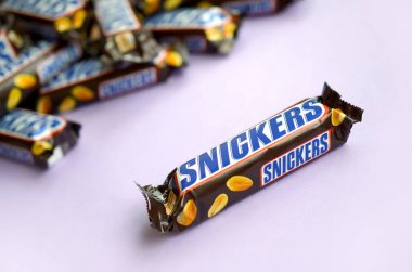 Birçok Snickers çikolatası pastel leylak kağıdının üzerinde yatar. Snickers çikolataları Mars Anonim Şirketi tarafından üretilir. Snickers 1930 yılında Franklin Clarence Mars tarafından yaratıldı.