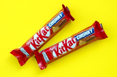 Kit Kat chocolate bars in red wrapping lies on bright yellow background. Kit kat created by Rowntree's of York in United Kingdom and is now produced globally by Nestle