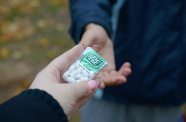 Kharkov, Ukrayna - 26 Ekim 2019: Genç adam sonbahar parkındaki kıza Tic Tac paketi götürdü. Tic Tac, Ferrero 'nun taze nane tadı nedeniyle popülerdir.