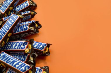 Birçok Snickers çikolatası pastel turuncu kağıdın üzerinde yatar. Snickers çikolataları Mars Anonim Şirketi tarafından üretilir. Snickers 1930 yılında Franklin Clarence Mars tarafından yaratıldı.