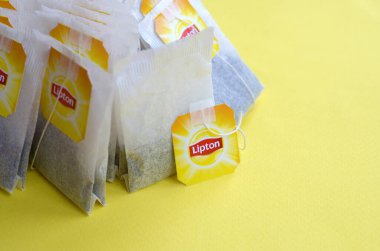 Pastel sarı yüzeyde Lipton Sarı Etiketli siyah çay poşetleri. Yaklaş. Lipton dünyaca ünlü bir çay türüdür.