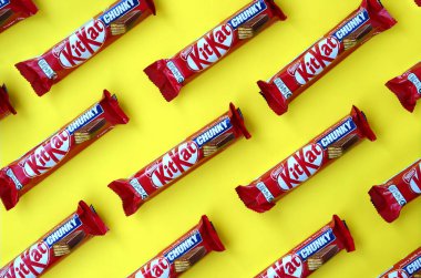 Kırmızı ambalajlı Kit Kat çikolataları sarı arka planda yatıyor. Kit Kat, Birleşik Krallık 'ta Rowntree' s of York tarafından yaratıldı ve şimdi küresel olarak Nestle tarafından üretiliyor.