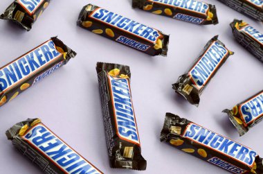 Birçok Snickers çikolatası pastel leylak kağıdının üzerinde yatar. Snickers çikolataları Mars Anonim Şirketi tarafından üretilir. Snickers 1930 yılında Franklin Clarence Mars tarafından yaratıldı.