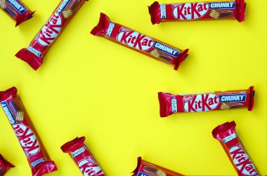 Kırmızı ambalajlı Kit Kat çikolataları sarı arka planda yatıyor. Kit Kat, Birleşik Krallık 'ta Rowntree' s of York tarafından yaratıldı ve şimdi küresel olarak Nestle tarafından üretiliyor.
