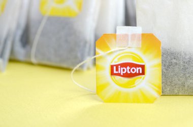 Pastel sarı yüzeyde Lipton Sarı Etiketli siyah çay poşetleri. Yaklaş. Lipton dünyaca ünlü bir çay türüdür.