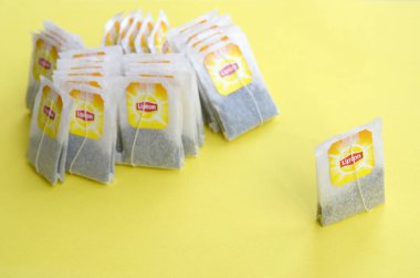 Pastel sarı yüzeyde Lipton Sarı Etiketli siyah çay poşetleri. Yaklaş. Lipton dünyaca ünlü bir çay türüdür.