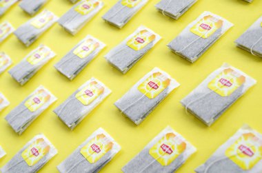 Pastel sarı yüzeyde Lipton Sarı Etiketli siyah çay poşetleri vardı. Lipton dünyaca ünlü bir çay türüdür.