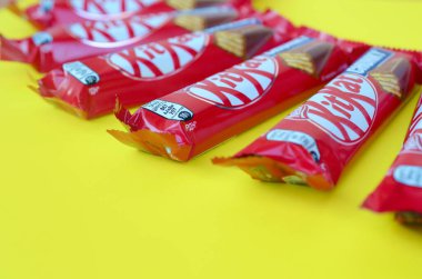 Kırmızı ambalajlı Kit Kat çikolataları sarı arka planda yatıyor. Kit Kat, Birleşik Krallık 'ta Rowntree' s of York tarafından yaratıldı ve şimdi küresel olarak Nestle tarafından üretiliyor.