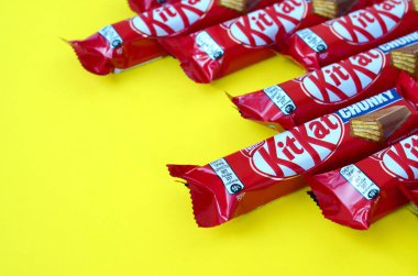 Kırmızı ambalajlı Kit Kat çikolataları sarı arka planda yatıyor. Kit Kat, Birleşik Krallık 'ta Rowntree' s of York tarafından yaratıldı ve şimdi küresel olarak Nestle tarafından üretiliyor.