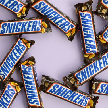 Birçok Snickers çikolatası pastel leylak kağıdının üzerinde yatar. Snickers çikolataları Mars Anonim Şirketi tarafından üretilir. Snickers 1930 yılında Franklin Clarence Mars tarafından yaratıldı.