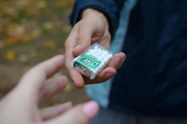Kharkov, Ukrayna - 26 Ekim 2019: Genç adam sonbahar parkındaki kıza Tic Tac paketi götürdü. Tic Tac, Ferrero 'nun taze nane tadı nedeniyle popülerdir.