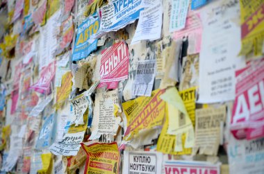KHARKOV, UKRAINE - OCTOBER 2, 2019: Grunge Message Board with many advertisement. People spreading advertising and information on white paper than post it on metal fence clipart
