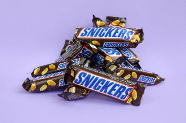 Birçok Snickers çikolatası pastel leylak kağıdının üzerinde yatar. Snickers çikolataları Mars Anonim Şirketi tarafından üretilir. Snickers 1930 yılında Franklin Clarence Mars tarafından yaratıldı.