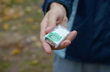 Kharkov, Ukrayna - 26 Ekim 2019: Genç adam sonbahar parkındaki kıza Tic Tac paketi götürdü. Tic Tac, Ferrero 'nun taze nane tadı nedeniyle popülerdir.