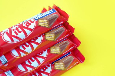 Kırmızı ambalajlı Kit Kat çikolataları sarı arka planda yatıyor. Kit Kat, Birleşik Krallık 'ta Rowntree' s of York tarafından yaratıldı ve şimdi küresel olarak Nestle tarafından üretiliyor.