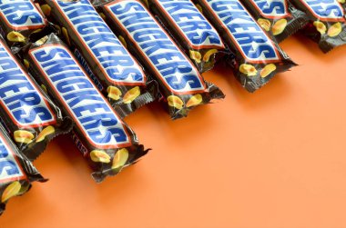 Birçok Snickers çikolatası pastel turuncu kağıdın üzerinde yatar. Snickers çikolataları Mars Anonim Şirketi tarafından üretilir. Snickers 1930 yılında Franklin Clarence Mars tarafından yaratıldı.