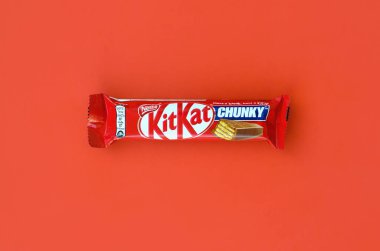 Kit Kat chocolate bar in red wrapping lies on bright red background. Kit kat created by Rowntree's of York in United Kingdom and is now produced globally by Nestle