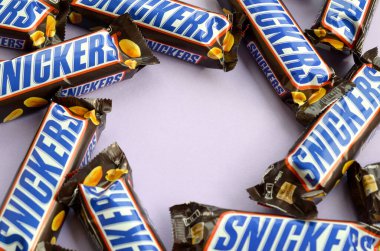 Birçok Snickers çikolatası pastel leylak kağıdının üzerinde yatar. Snickers çikolataları Mars Anonim Şirketi tarafından üretilir. Snickers 1930 yılında Franklin Clarence Mars tarafından yaratıldı.