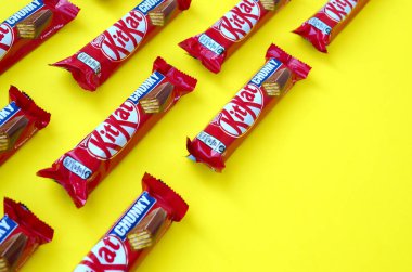 Kırmızı ambalajlı Kit Kat çikolataları sarı arka planda yatıyor. Kit Kat, Birleşik Krallık 'ta Rowntree' s of York tarafından yaratıldı ve şimdi küresel olarak Nestle tarafından üretiliyor.
