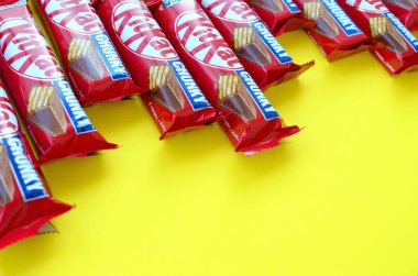 Kırmızı ambalajlı Kit Kat çikolataları sarı arka planda yatıyor. Kit Kat, Birleşik Krallık 'ta Rowntree' s of York tarafından yaratıldı ve şimdi küresel olarak Nestle tarafından üretiliyor.