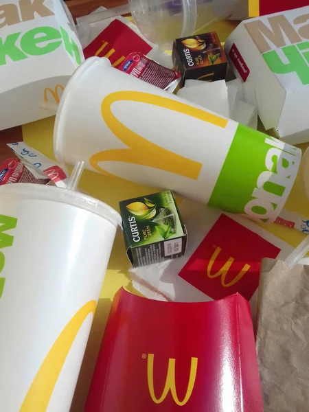 Embalagens de papel usadas e embalagens descartáveis com design e logotipo McDonalds em pilha na mesa. McDonalds reciclar lixo após o uso — Fotografia de Stock