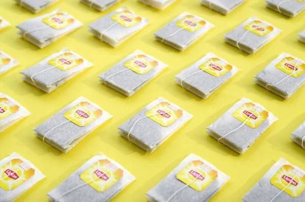 Colocación plana de bolsas de té negras Lipton Yellow Label sobre una superficie de color amarillo pastel. Lipton es una marca de té mundialmente famosa —  Fotos de Stock