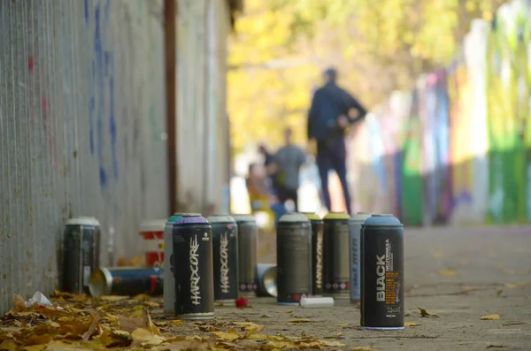 KHARKOV, UCRANIA - 19 DE OCTUBRE DE 2019: latas de spray usadas para pintar graffiti de muchas marcas de pintura al aire libre en otoño y artista en proceso de pintura — Foto de Stock