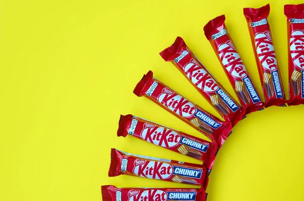 Kit Kat barras de chocolate en rojo envoltura se encuentra en el fondo amarillo. Kit kat creado por Rowntree 's de York en Reino Unido y ahora es producido globalmente por Nestle —  Fotos de Stock