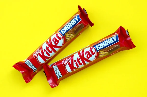Kit Kat chocolate bars in red wrapping lies on bright yellow background. Kit kat created by Rowntree's of York in United Kingdom and is now produced globally by Nestle — 图库照片