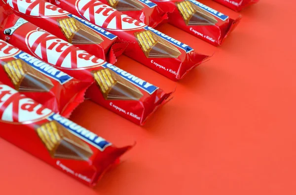 Kit Kat barras de chocolate em vermelho embrulho mentiras sobre fundo amarelo agora é produzido globalmente por Nestlé. Faça uma pausa - tenha um Kit Kat — Fotografia de Stock