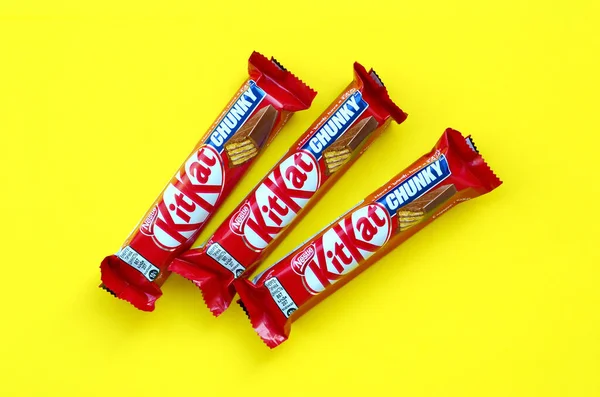 Kit Kat barres de chocolat dans un emballage rouge repose sur un fond jaune vif. Kit kat créé par Rowntree de York au Royaume-Uni et est maintenant produit dans le monde entier par Nestlé — Photo