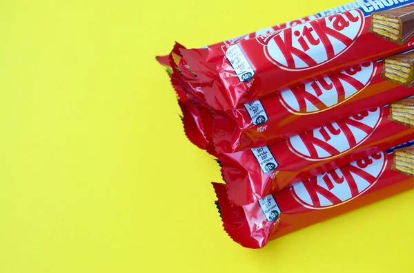 Kit Kat barres de chocolat dans un emballage rouge repose sur fond jaune. Kit kat créé par Rowntree de York au Royaume-Uni et est maintenant produit dans le monde entier par Nestlé — Photo