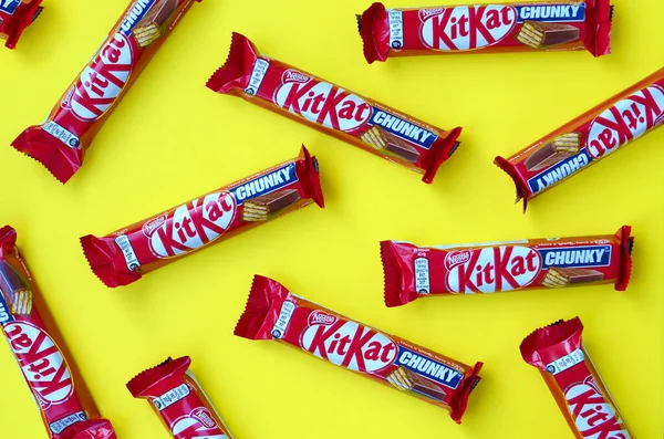 Kit Kat barres de chocolat dans un emballage rouge repose sur fond jaune. Kit kat créé par Rowntree de York au Royaume-Uni et est maintenant produit dans le monde entier par Nestlé — Photo