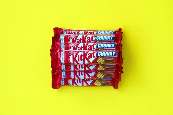 红色包装的Kit Kat巧克力棒躺在黄色背景上。 Kit kat由英国York的Rowntree's创作，目前由Nestle在全球发行 — 图库照片