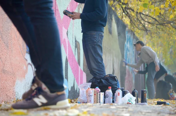KHARKOV, UCRANIA - 19 DE OCTUBRE DE 2019: latas de spray usadas para pintar graffiti de muchas marcas de pintura al aire libre en otoño y artista en proceso de pintura — Foto de Stock