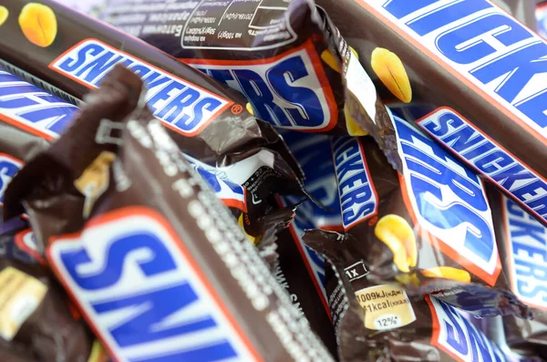 Muchas barras de chocolate Snickers apiladas de cerca. Las barras Snickers son producidas por Mars Incorporated. Snickers fue creado por Franklin Clarence Mars en 1930 —  Fotos de Stock