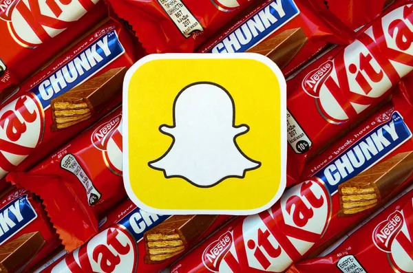 Snapchat paper logo on many Kit Kat chocolate covered wafer bars in red wrapping. Advertising chocolate product in Snapchat social network and world wide web – stockfoto