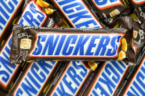 Många Snickers chokladkakor staplade på nära håll. Snickers barer tillverkas av Mars Incorporated. Snickers skapades av Franklin Clarence Mars 1930 — Stockfoto